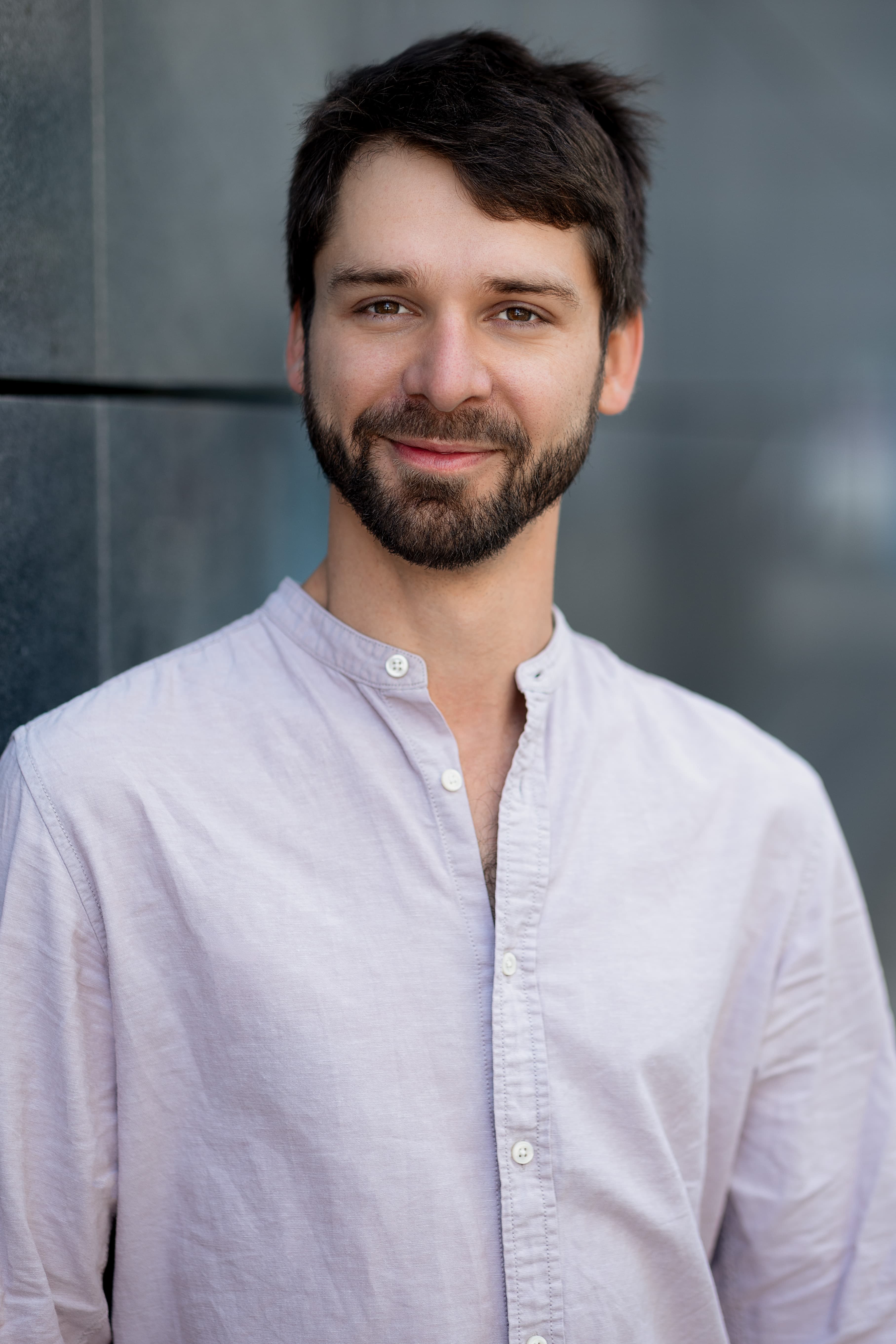 Portrait of Clemens Malkawi in front of a cool-grey architectural surface.